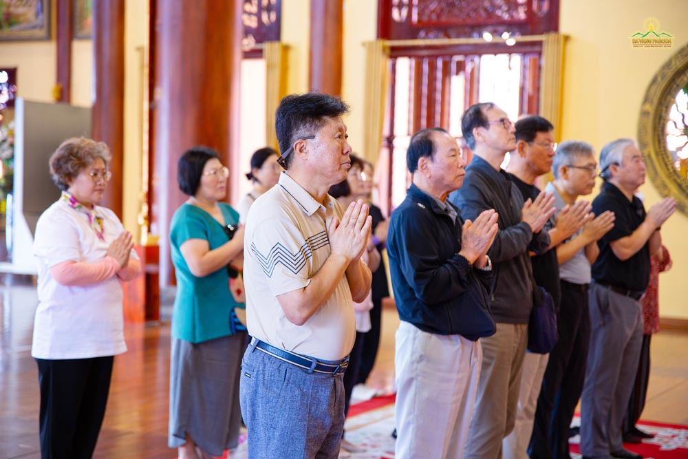 The group respectfully clasped their hands and concentrated, following the monks' instruction