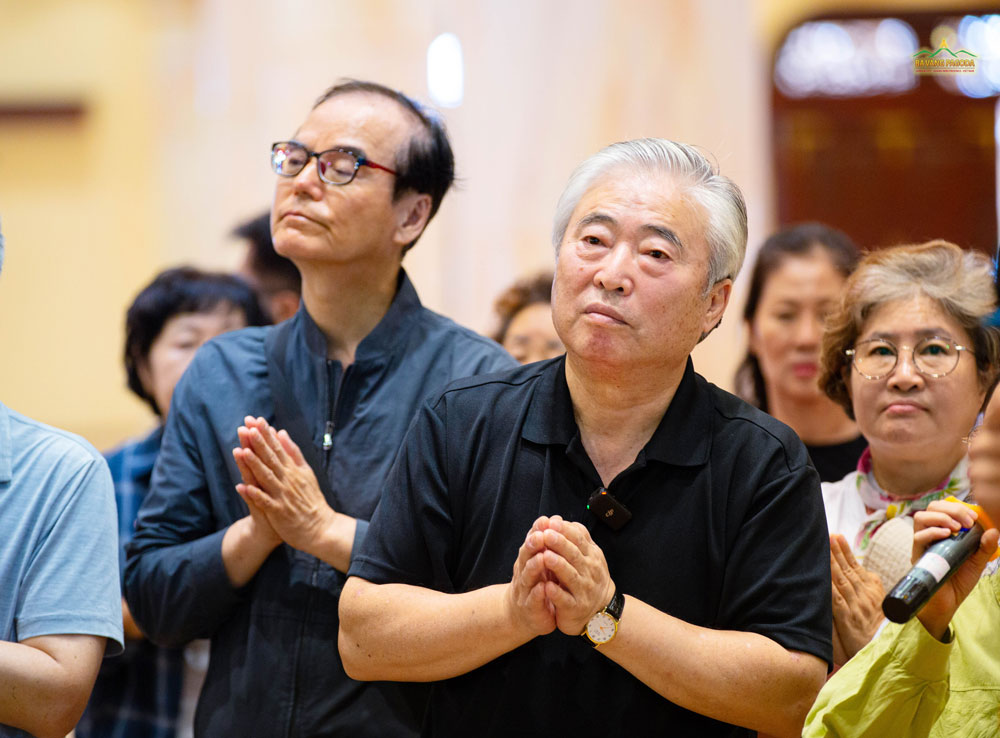 The delegation listened attentively to the monks sharing the meaning of the statue of the Buddha entering Nirvana on the first floor of the Great Lecture Hall.