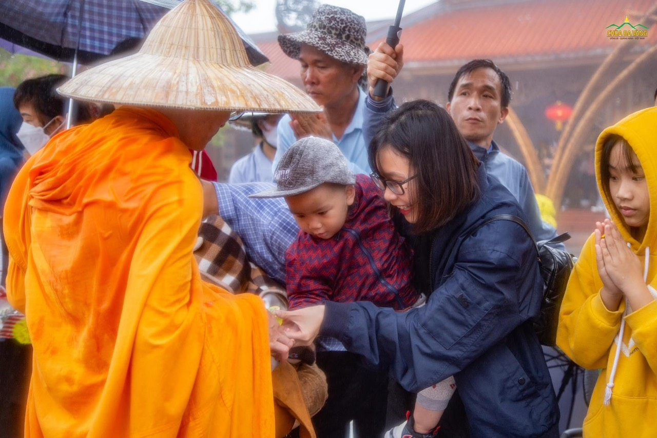 How happy is that the family met Buddhism! The baby, supported by his mom, offers alms to monks, sowing an auspicious seed for his present and future lives.