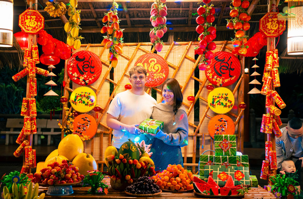 A young couple took a souvenir picture in a colorful Tet setting