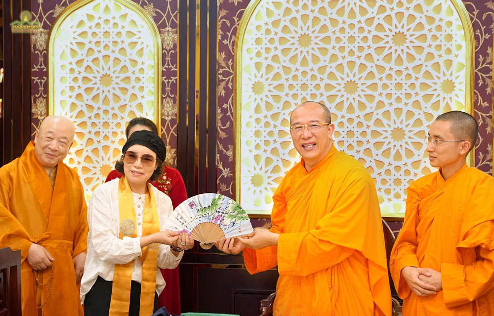 A Korean Buddhist offered Thay Thich Truc Thai Minh a paper fan, which was calligraphed by Most Venerable Jeong Beom-ryun and painted with drawings by the Buddhist herself. 한국 흥륜사 불교신자 석죽태명스님에게 종이부채를 선물 절단하고 있다. 이 종이부채 소재가 정법륜스님 직접 글씨를 쓰고 불교신다 그림을 그린 것으로 알려졌다.