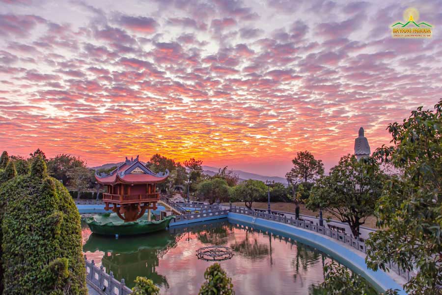 The Half Moon Lake of Ba Vang Pagoda reflects the sky at dawn above Thanh Dang Mountain.