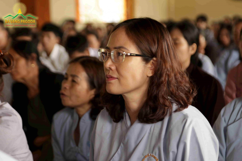 A woman attentively listens to teachings at the ceremony of transmitting five precepts
