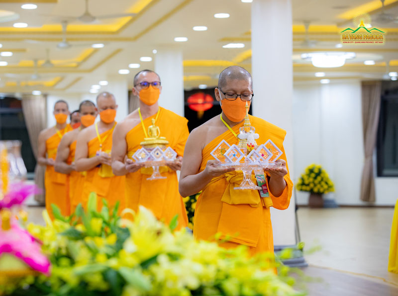 Thai Buddhist monks carefully carrying offerings made to Ba Vang Pagoda, Vietnam.