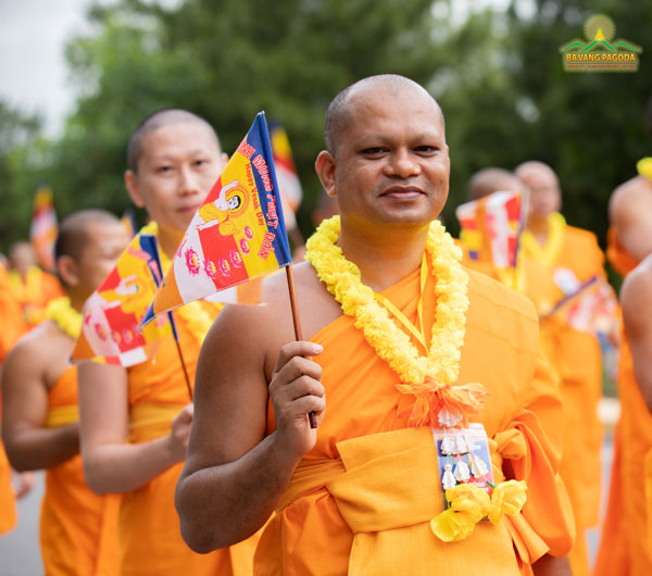 A Bangladeshi monk happily waving the Buddist flag in VESAK celebration 2022 at Ba Vang Pagoda
