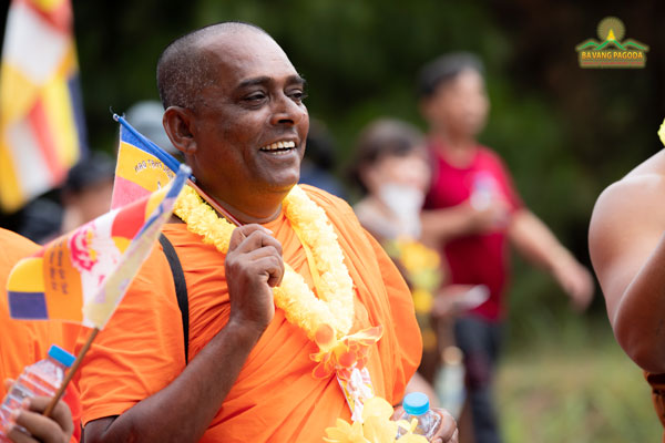 A Sri Lankan monk happily waving a Buddhist flag in VESAK celebration 2022 at Ba Vang Pagoda